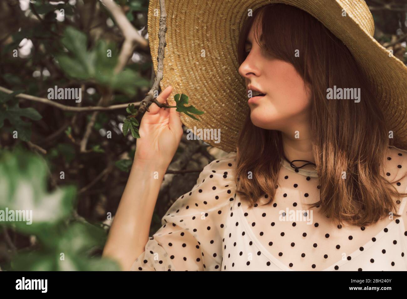 Ritratto di donna con cappello di paglia e abito vintage ad un albero Foto Stock