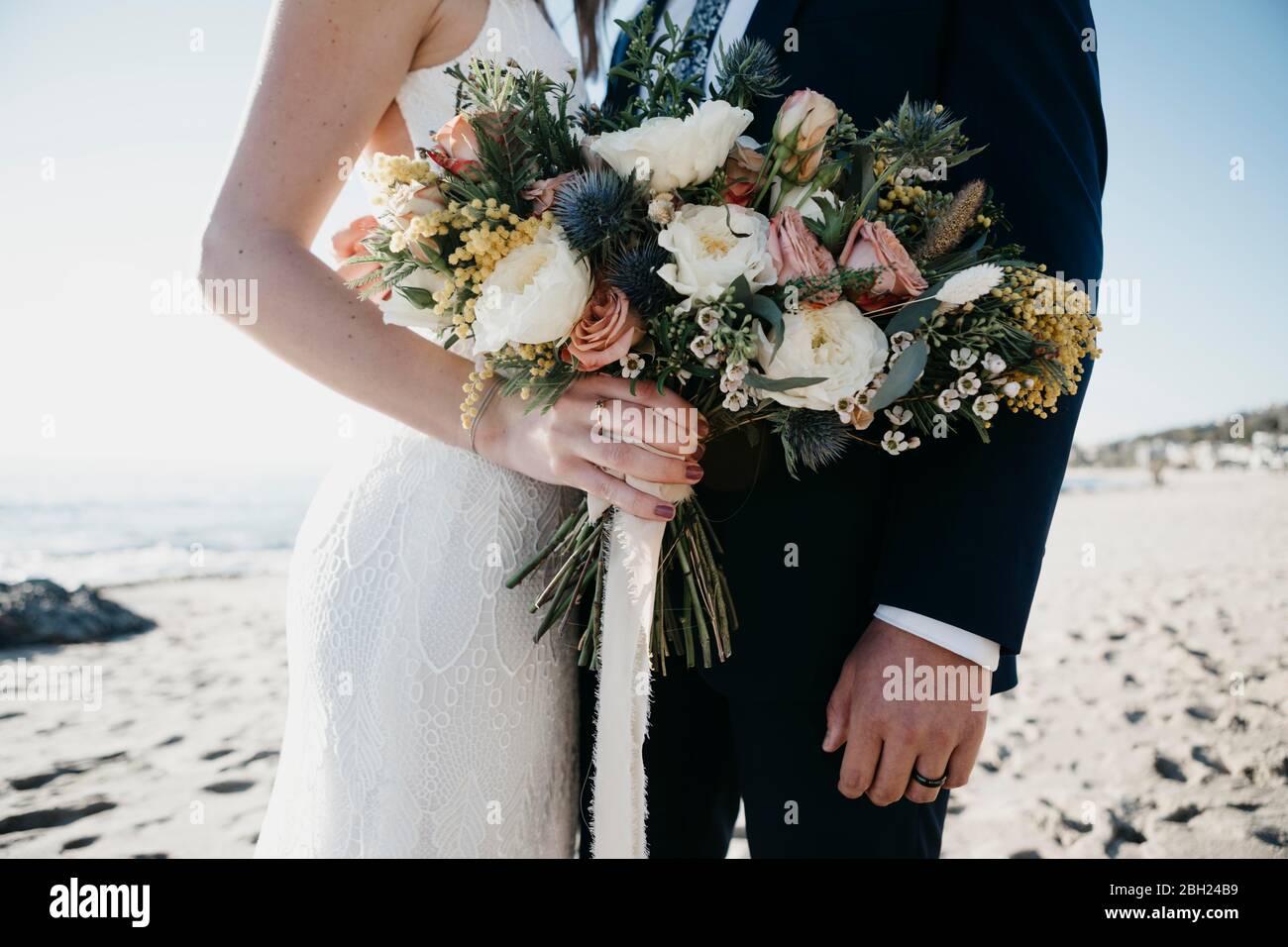 Coppia nuziale con bouquet nuziale in spiaggia Foto Stock