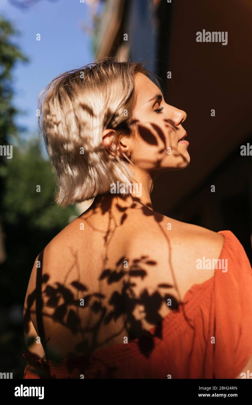 Profilo di giovane donna con ombre di foglie su faccia e schiena Foto Stock