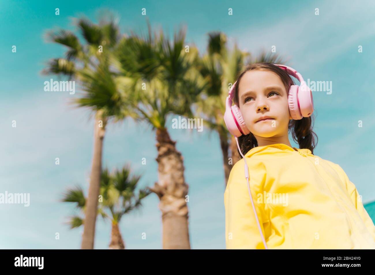 Ritratto di una bambina seria che ascolta musica con le cuffie all'aperto Foto Stock