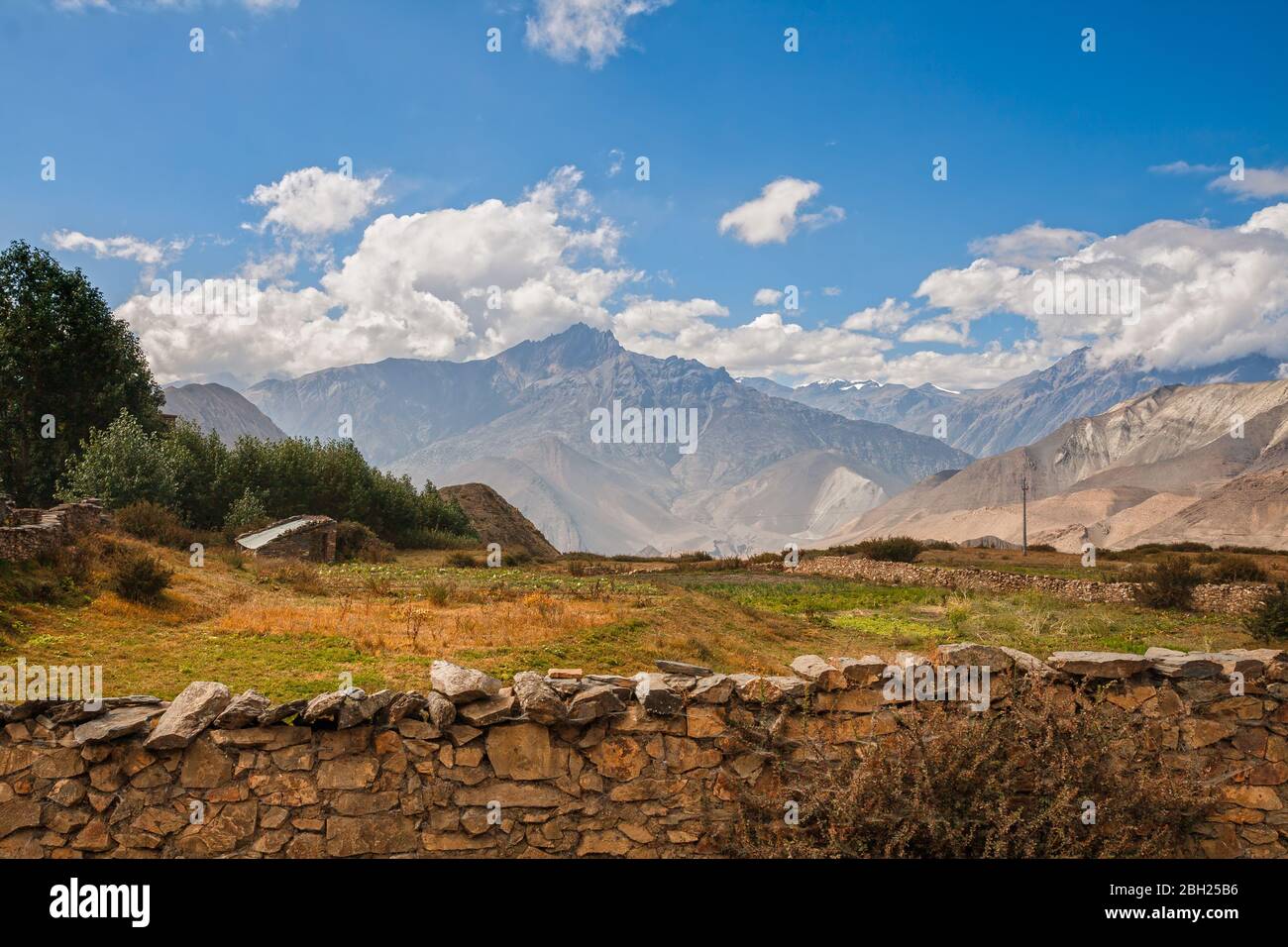 Paesaggio Himalayano, campi e giardini dietro recinzioni di pietra ai piedi delle montagne, Mustang inferiore, Nepal. Foto Stock
