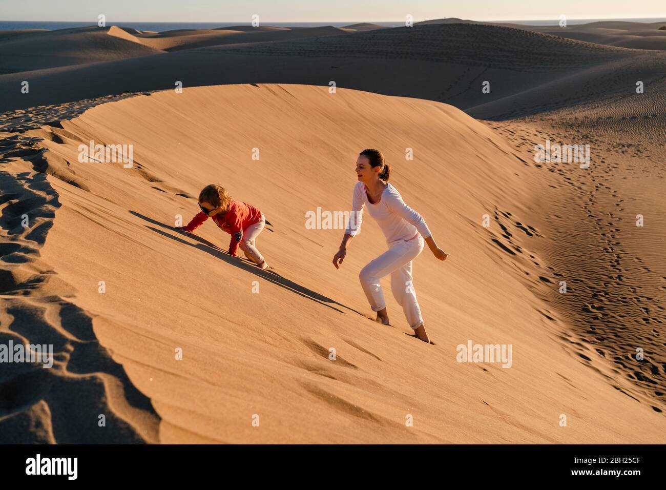 Madre e figlia che arrampicano su duna di sabbia, Gran Canaria, Spagna Foto Stock