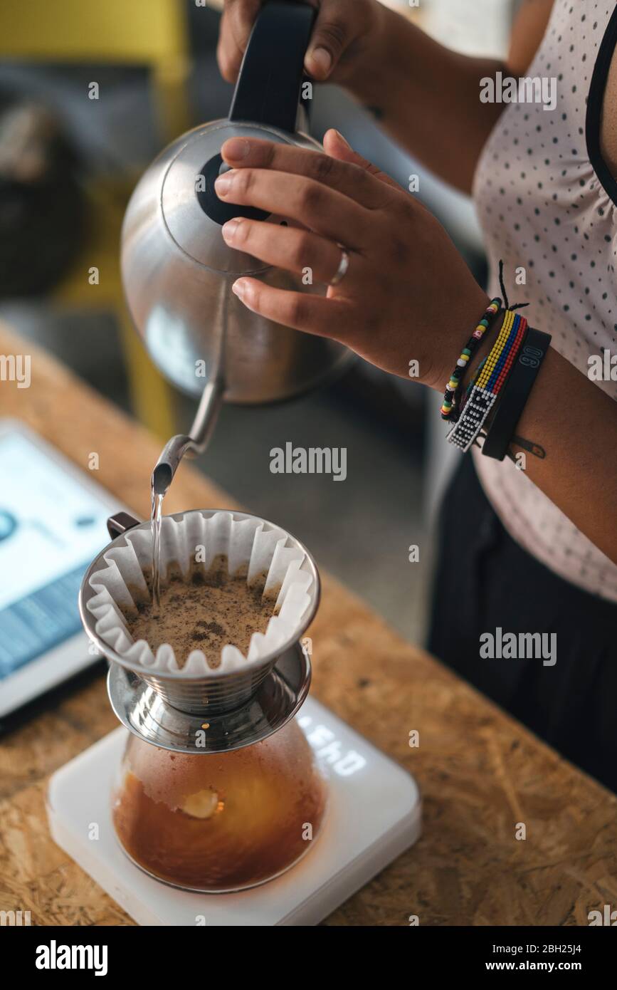 Donna che lavora in una torrefazione del caffè preparando caffè filtrato fresco Foto Stock