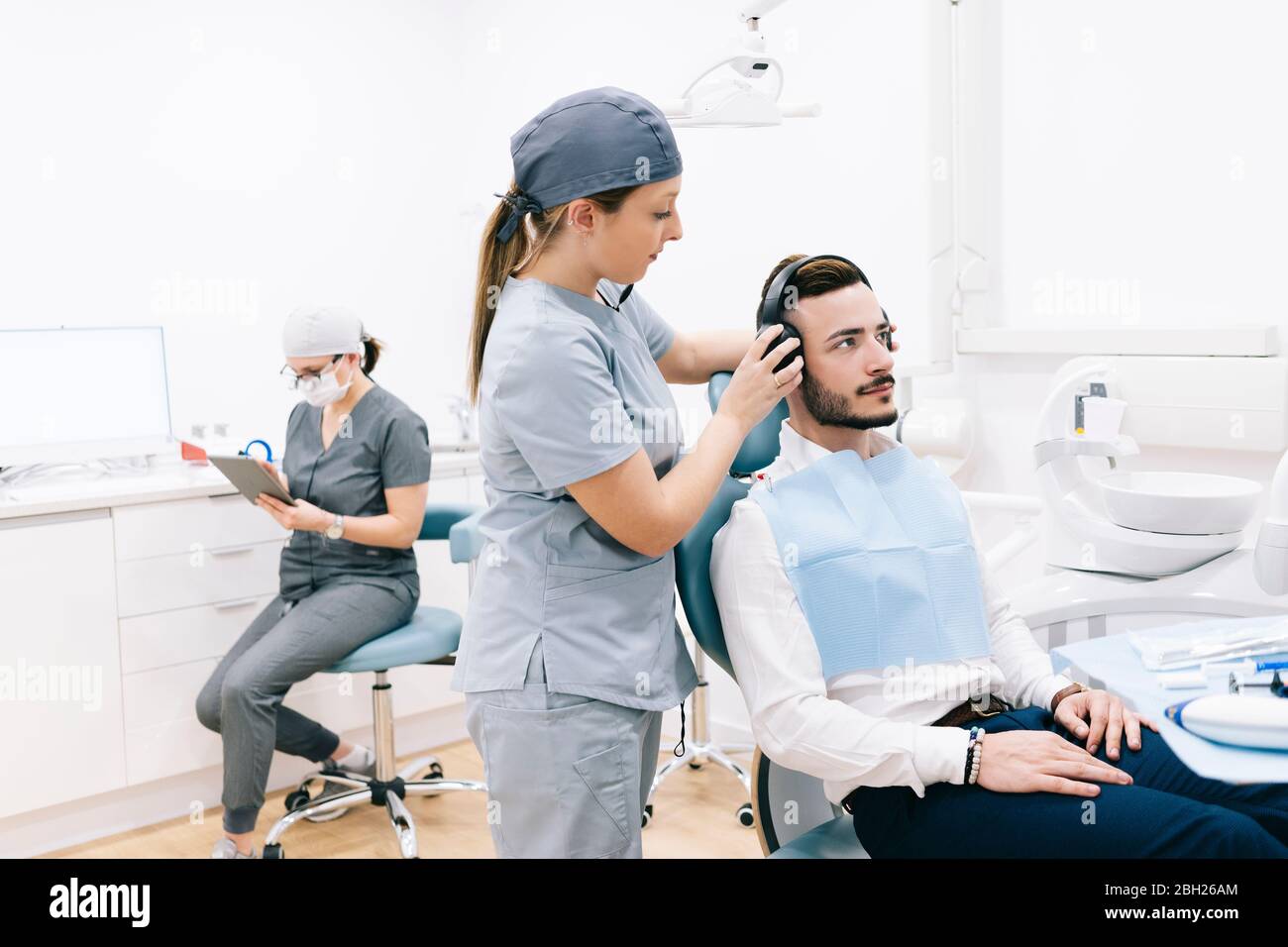 Segreteria medica preparazione del trattamento dentale indossare le cuffie sulla testa del paziente Foto Stock