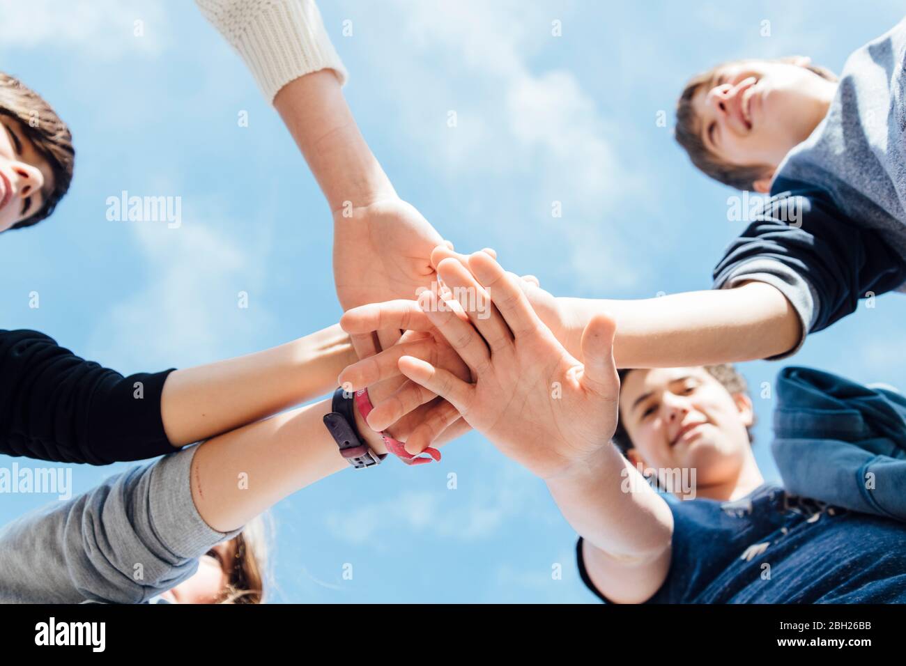 Cinque amici che accatastano le mani, visti dal basso Foto Stock