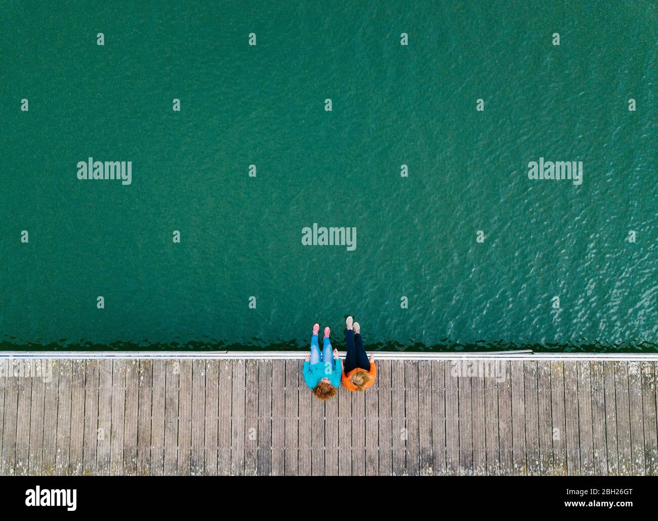 Due amici seduti fianco a fianco sul molo, Valdemurio Reservoir, Asturias, Spagna Foto Stock