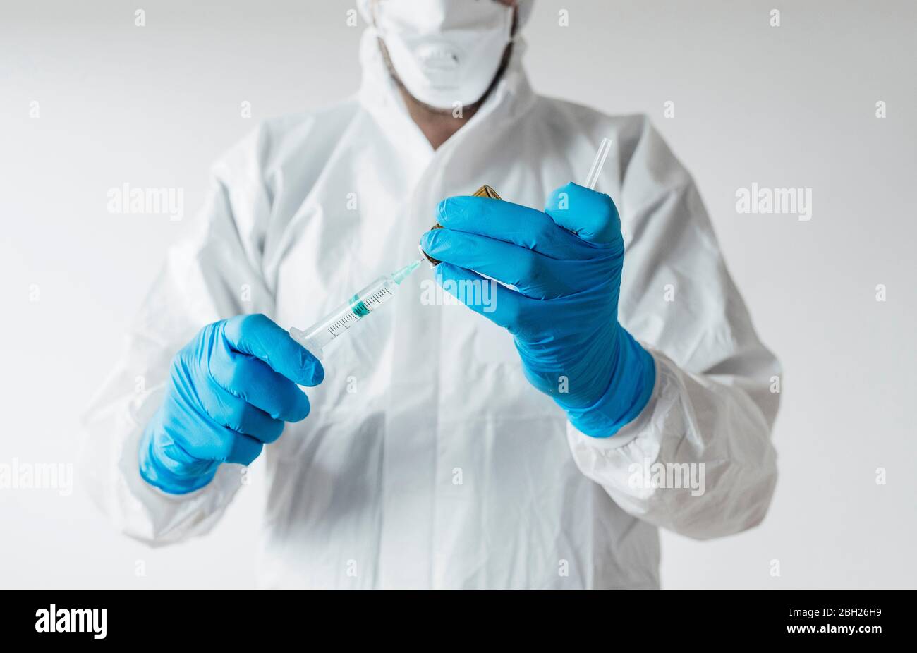 Tecnico di laboratorio che indossa indumenti protettivi, che tiene il vaccino Foto Stock