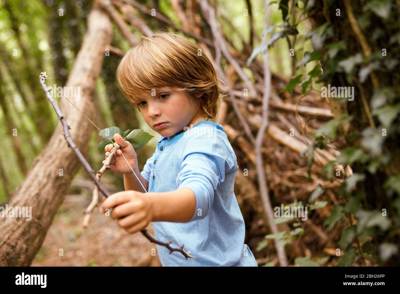 Ragazzo che gioca con arco e freccia nella foresta Foto Stock