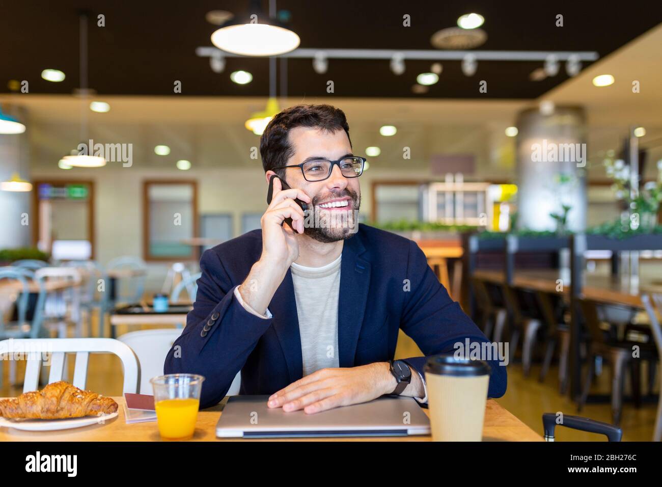 Ritratto di felice uomo d'affari al telefono in una caffetteria Foto Stock