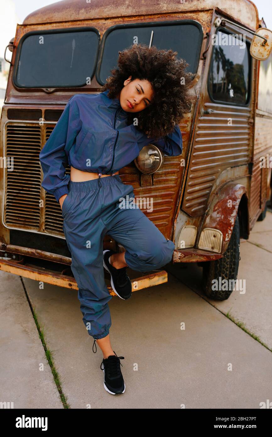 Ritratto di giovane donna elegante che indossa tuta da ginnica appoggiata  al vecchio furgone Foto stock - Alamy
