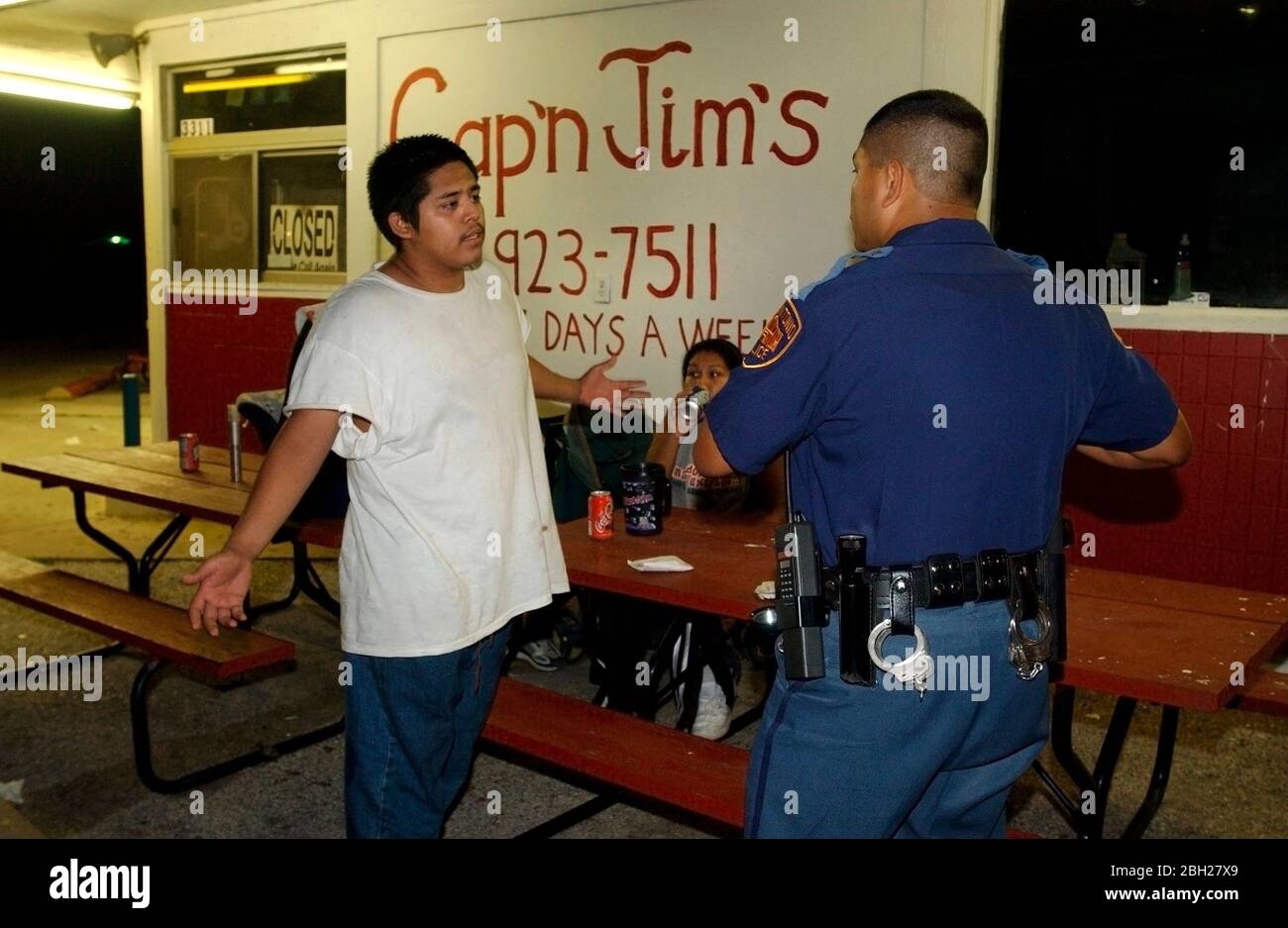 San Antonio, Texas Agosto 2003: Poliziotto e ragazzo che parlano di fronte al fornitore di cibo di Cap'n Jim a tarda notte NMB ©Bob Daemmrich per uso editoriale Foto Stock