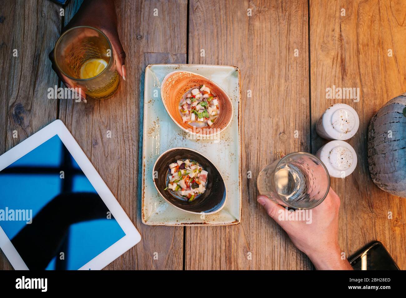 Due persone sedute al ristorante, mangiando e bevendo, con tablet digitale sul tavolo Foto Stock