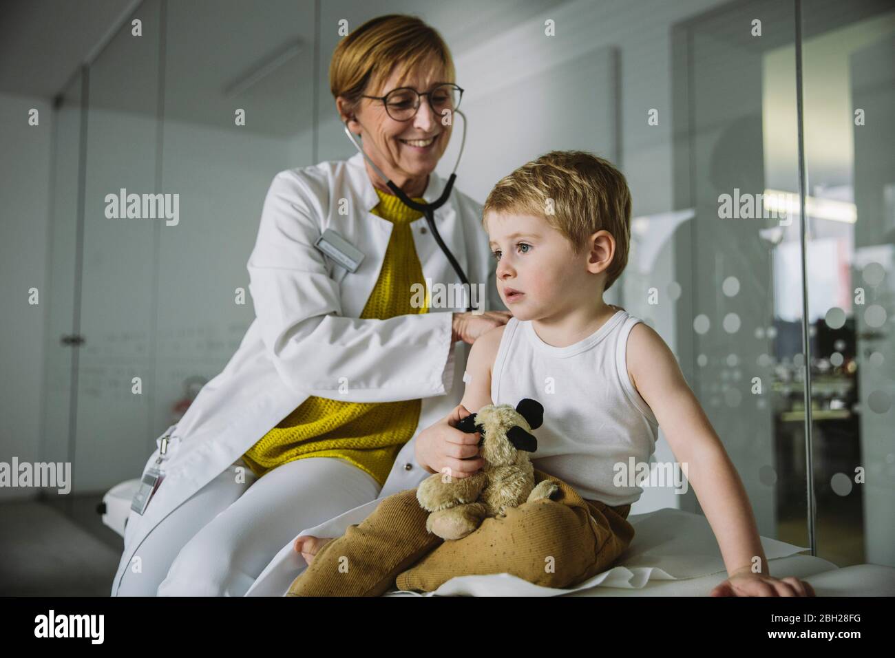 Medico che esamina il bambino con uno stetoscopio Foto Stock