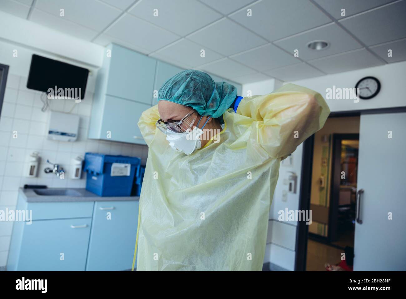 Medico che mette su dispositivi di protezione personale in ospedale Foto Stock