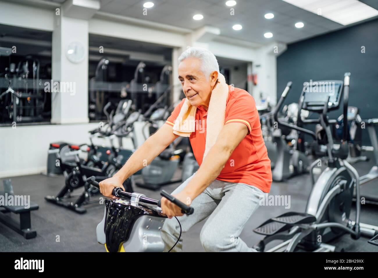 Uomo anziano che pratica alla macchina di esercitazione in palestra Foto Stock