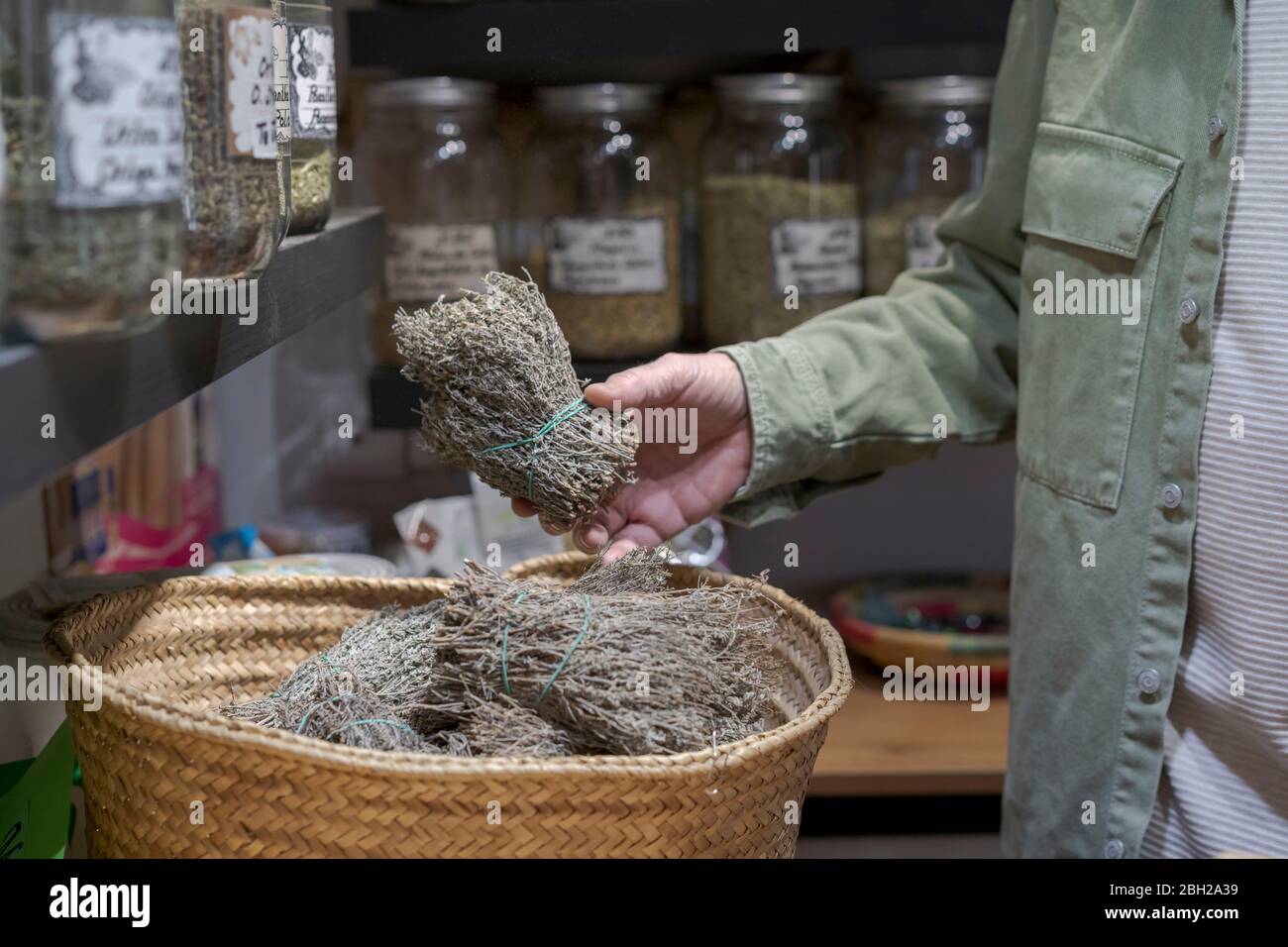 Primo piano di uomo anziano che tiene mazzo di piante secche in un piccolo negozio Foto Stock