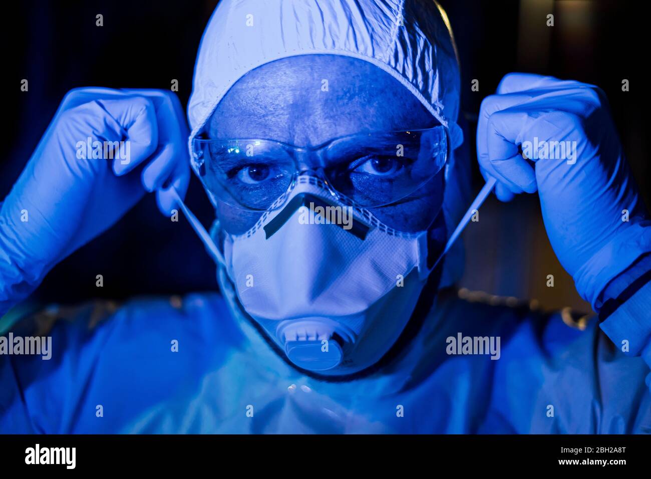 Medico indossando indumenti protettivi, indossando la maschera facciale Foto Stock