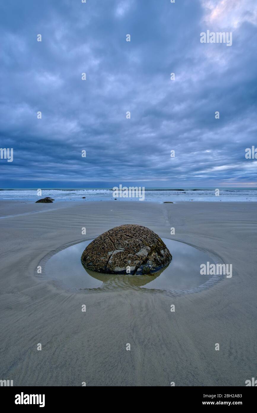 Nuova Zelanda, Otago, Moeraki, lunga esposizione di nuvole su solco Moeraki Boulder giace su Koekohe Beach al crepuscolo Foto Stock