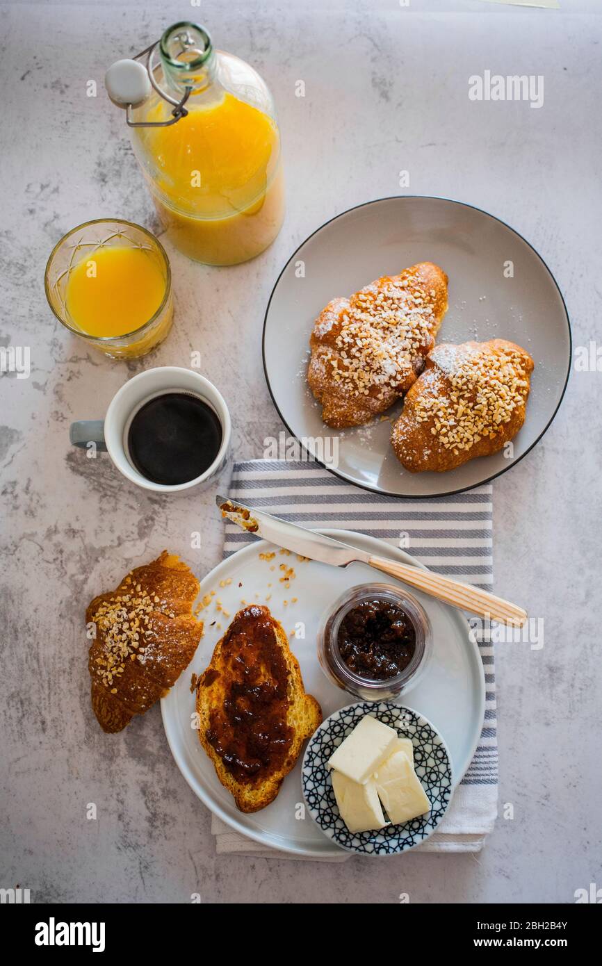 Tazza di caffè, burro, succo d'arancia e brioche con marmellata di frutti di bosco Foto Stock