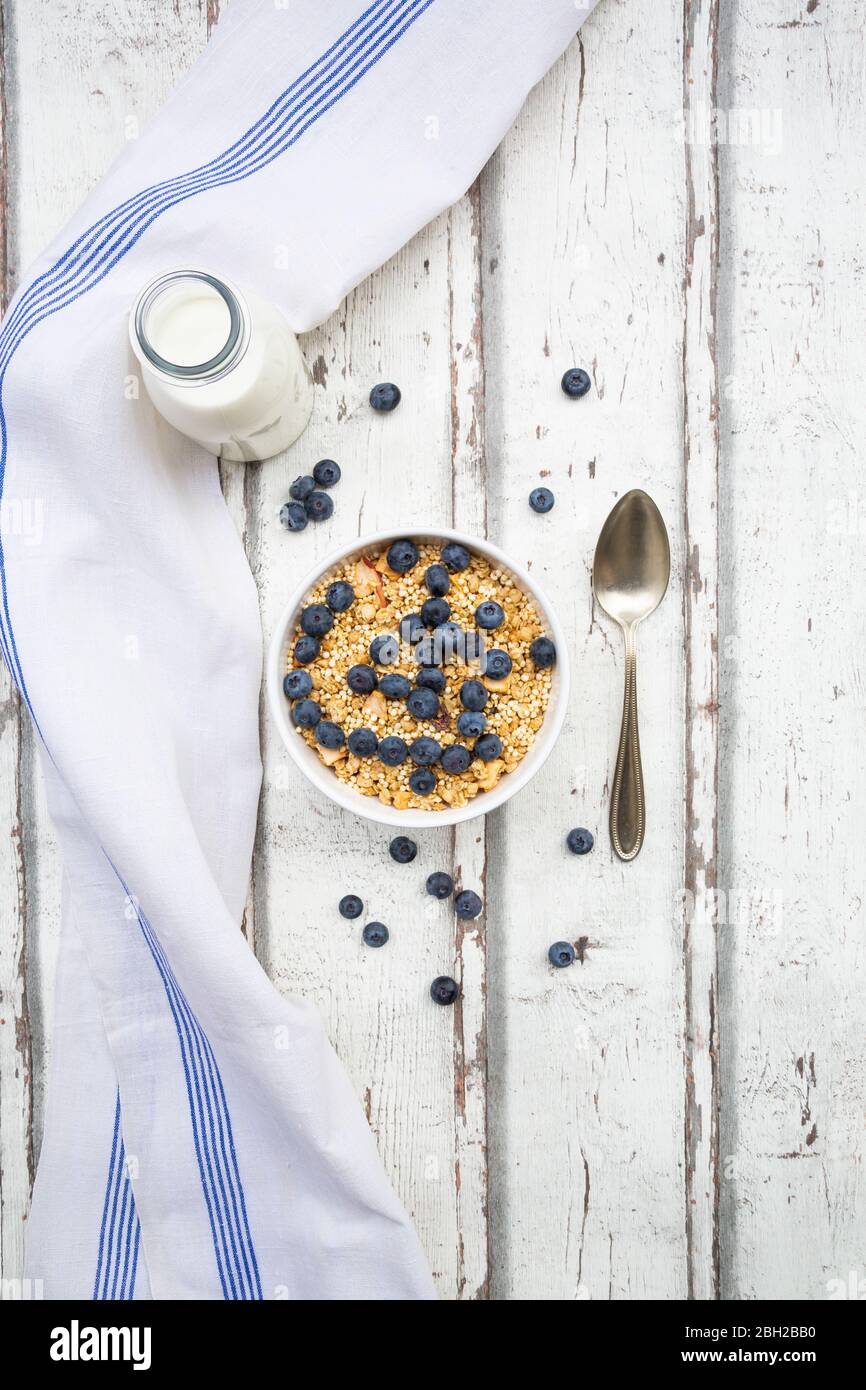 Bottiglia di latte, tovagliolo e ciotola di muesli con mirtilli Foto Stock