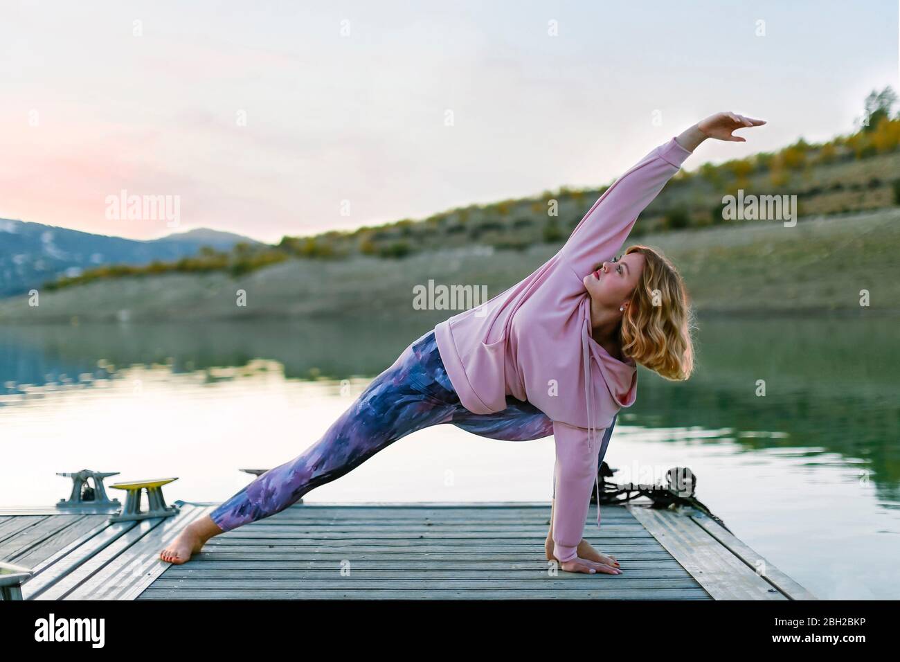 Giovane donna che fa yoga su un molo, posa triangolo Foto Stock