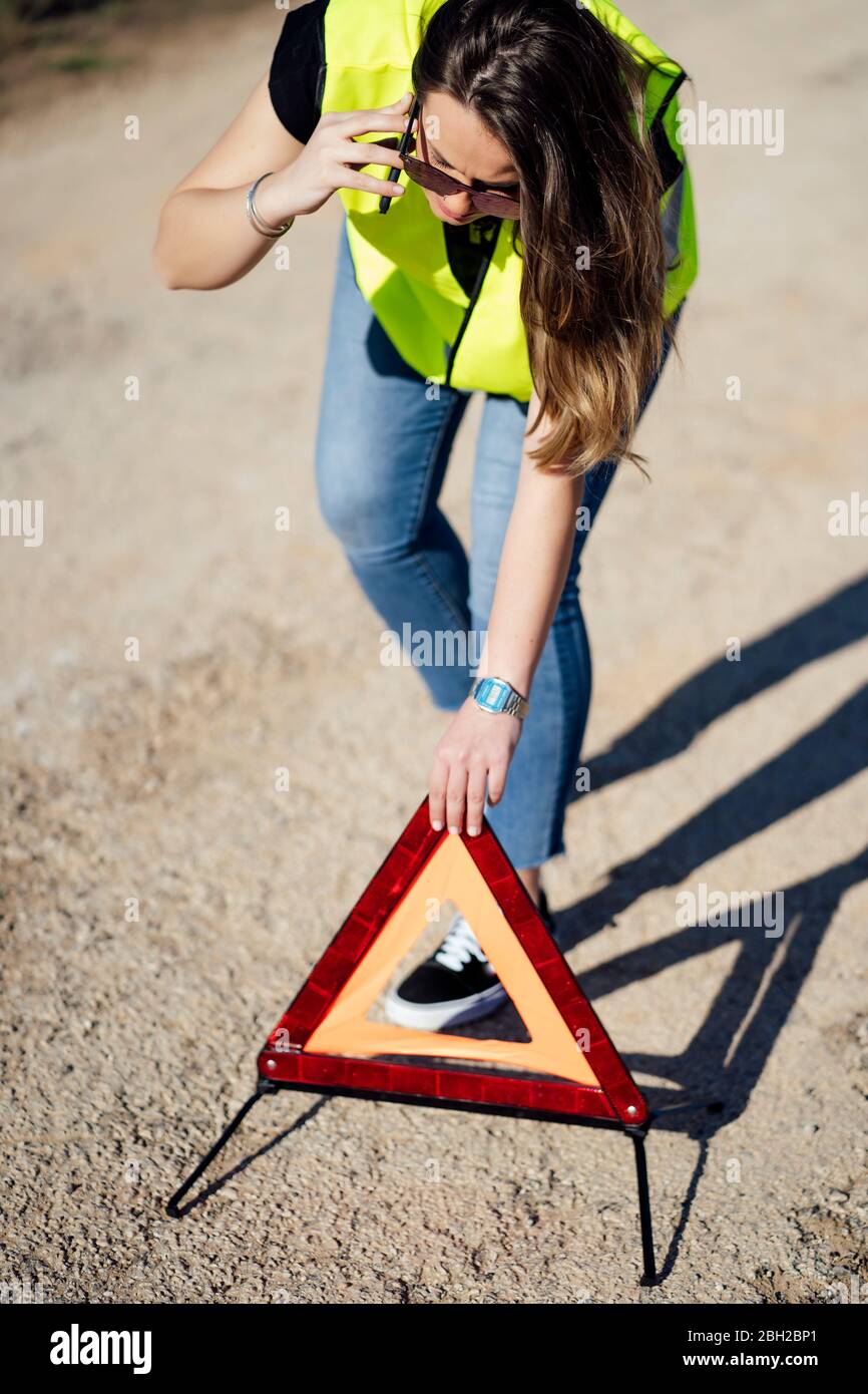 Donna che ha un triangolo di avvertimento di distacco di guasto Foto Stock