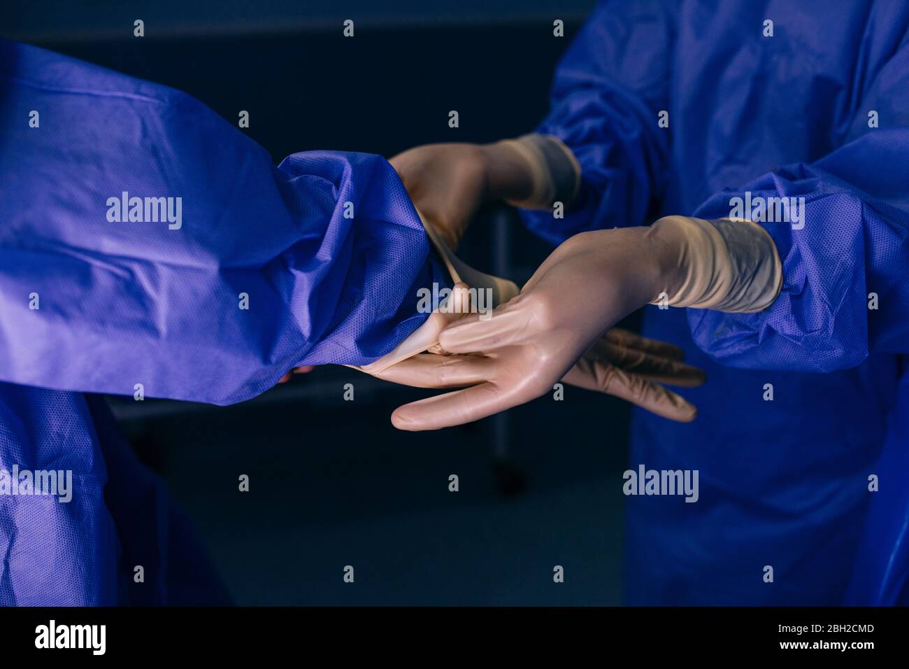 Infermiere della sala operatoria che aiuta il chirurgo a indossare i guanti prima di un intervento Foto Stock