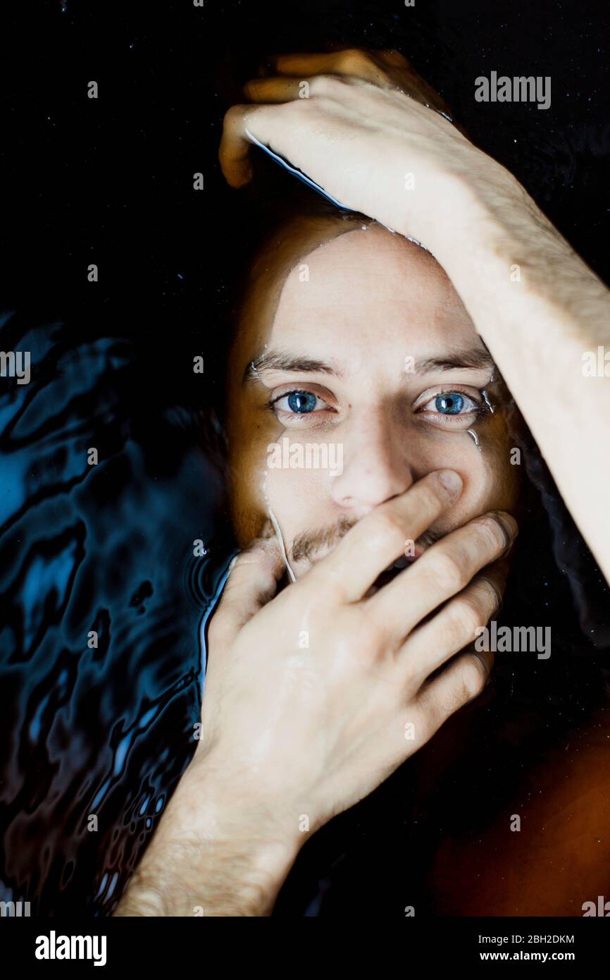 Ritratto di giovane uomo con occhi blu in acqua Foto Stock