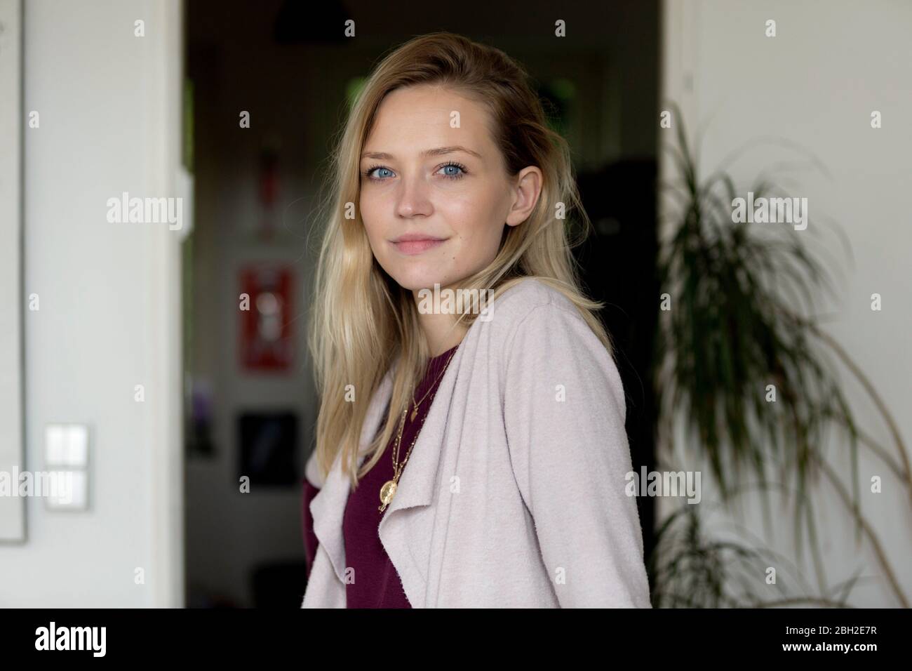 Ritratto di giovane bionda sorridente con occhi blu a casa Foto Stock