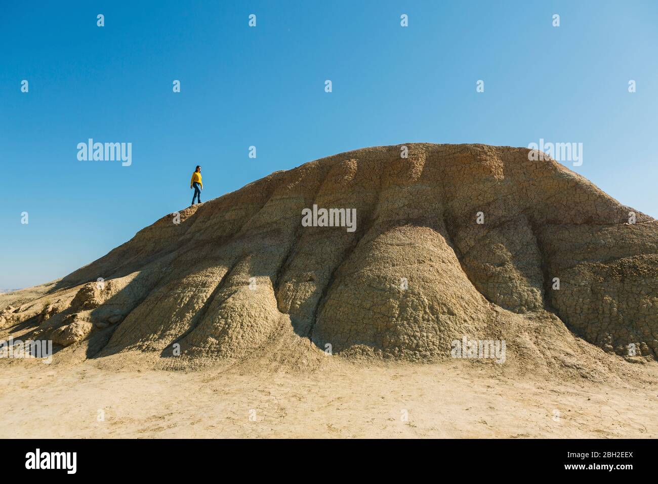 Donna che cammina su una collina in un paesaggio desertico di Bardenas Reales, Arguedas, Navarra, Spagna Foto Stock