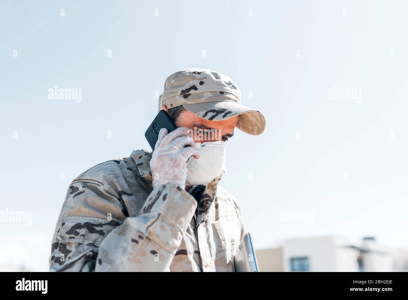 Soldato con maschera facciale in caso di emergenza, utilizzando smartphone Foto Stock