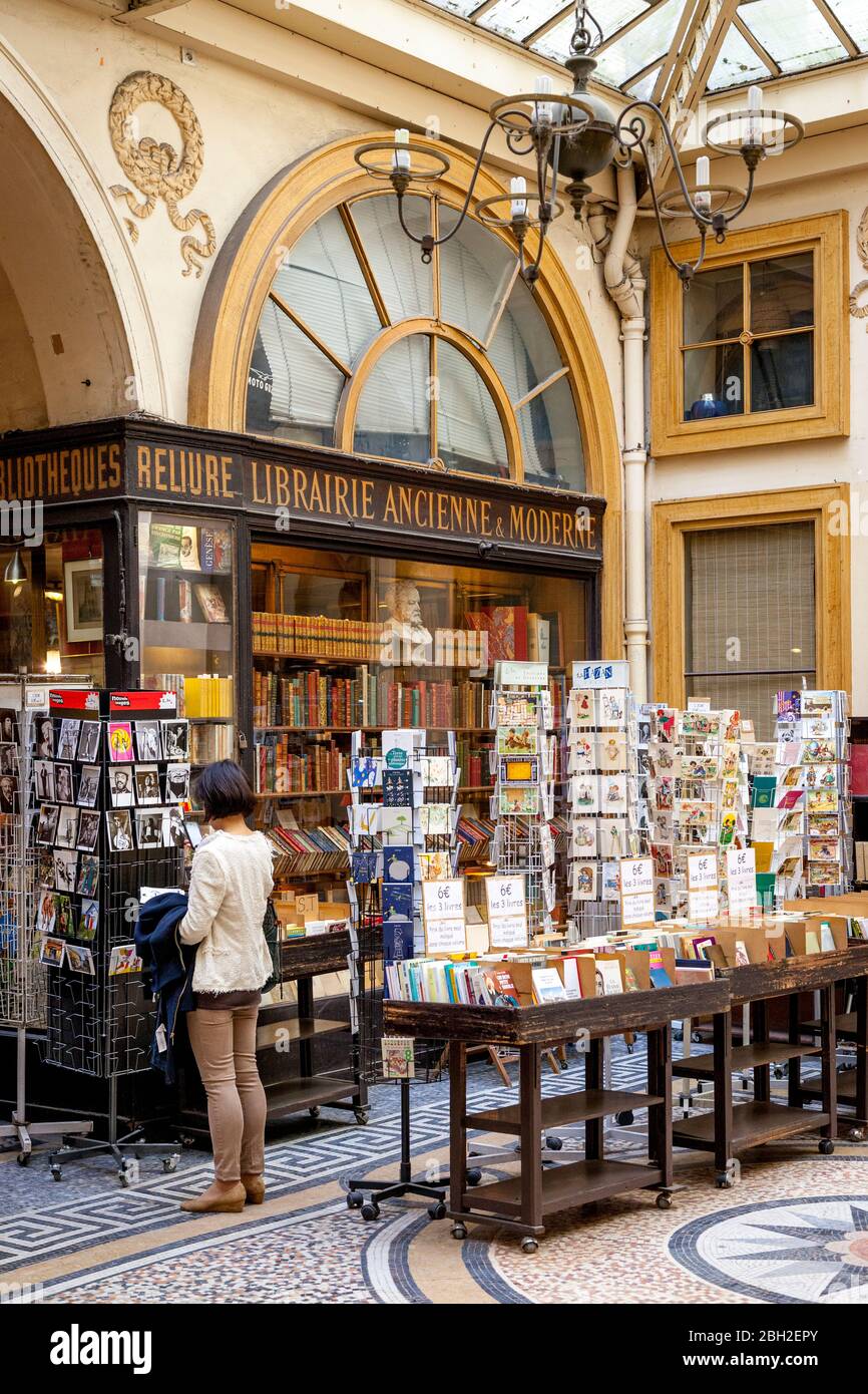 Giovane donna che acquista in una libreria di antiquariato a Passage Vivienne, Parigi, Francia Foto Stock