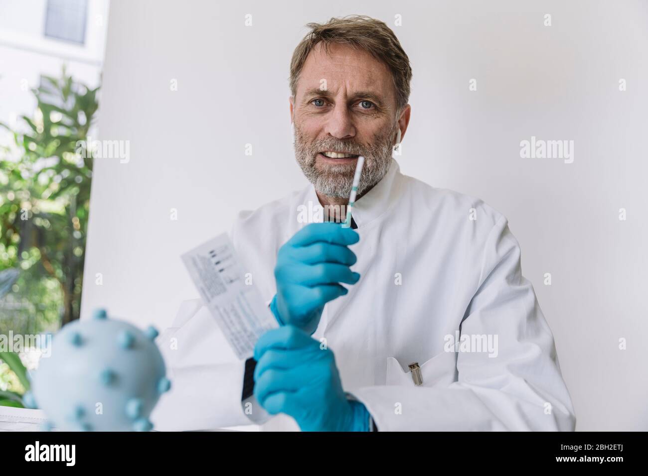 Ritratto dello scienziato che tiene in mano il dispositivo di test del flusso laterale Foto Stock