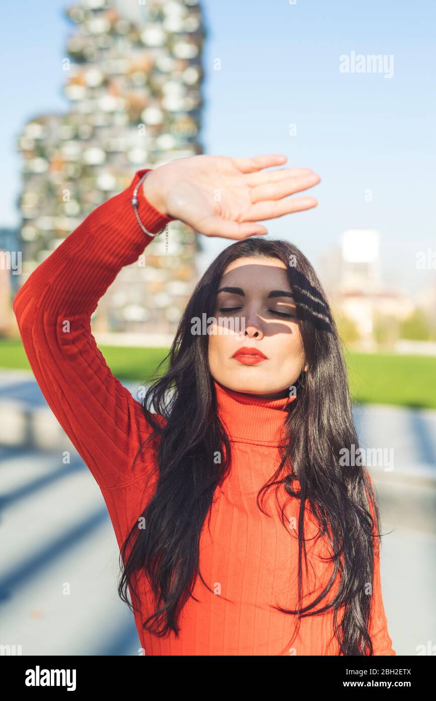 Ombra della mano sul pensieroso volto di donna durante la giornata di sole Foto Stock