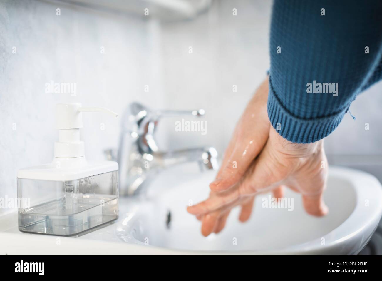 Uomo che lava le mani con sapone liquido, primo piano Foto Stock