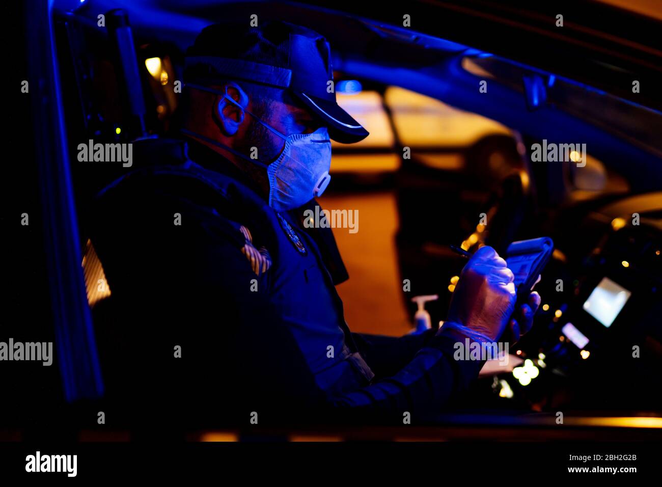 Poliziotto in missione di emergenza, seduto in auto, prendendo appunti Foto Stock