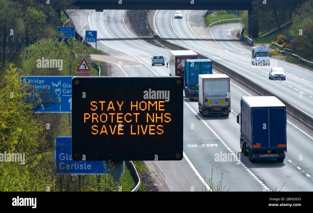 Castlecary, Scozia, Regno Unito. 23 aprile 2020. Cartello di avvertimento sull'autostrada M80 che consiglia agli automobilisti di rimanere a casa per proteggere l'NHS durante il blocco dei coronavirus nel Regno Unito. I volumi di traffico in autostrada rimangono molto bassi. Iain Masterton/Alamy Live News Foto Stock