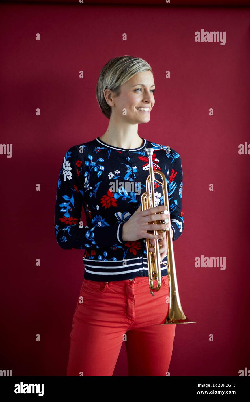 Donna bionda sorridente che tiene una tromba Foto stock - Alamy