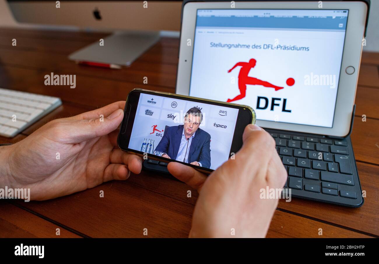 Warendorf, Germania. 23 aprile 2020. Un uomo guarda la mostra del suo smartphone, che mostra Christian Seifert, CEO e portavoce del Comitato Esecutivo della Lega di Calcio tedesca (DFL), durante una videoconferenza stampa dal vivo dopo l'incontro generale del DFL sulle conseguenze della pandemia di Corona. Credit: Guido Kirchner/dpa/Alamy Live News Foto Stock
