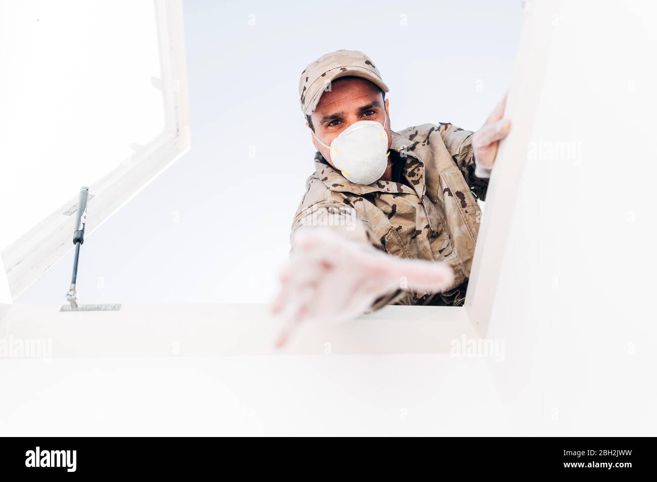 Soldato con maschera facciale in caso di emergenza, raggiungendo attraverso il lucernario Foto Stock