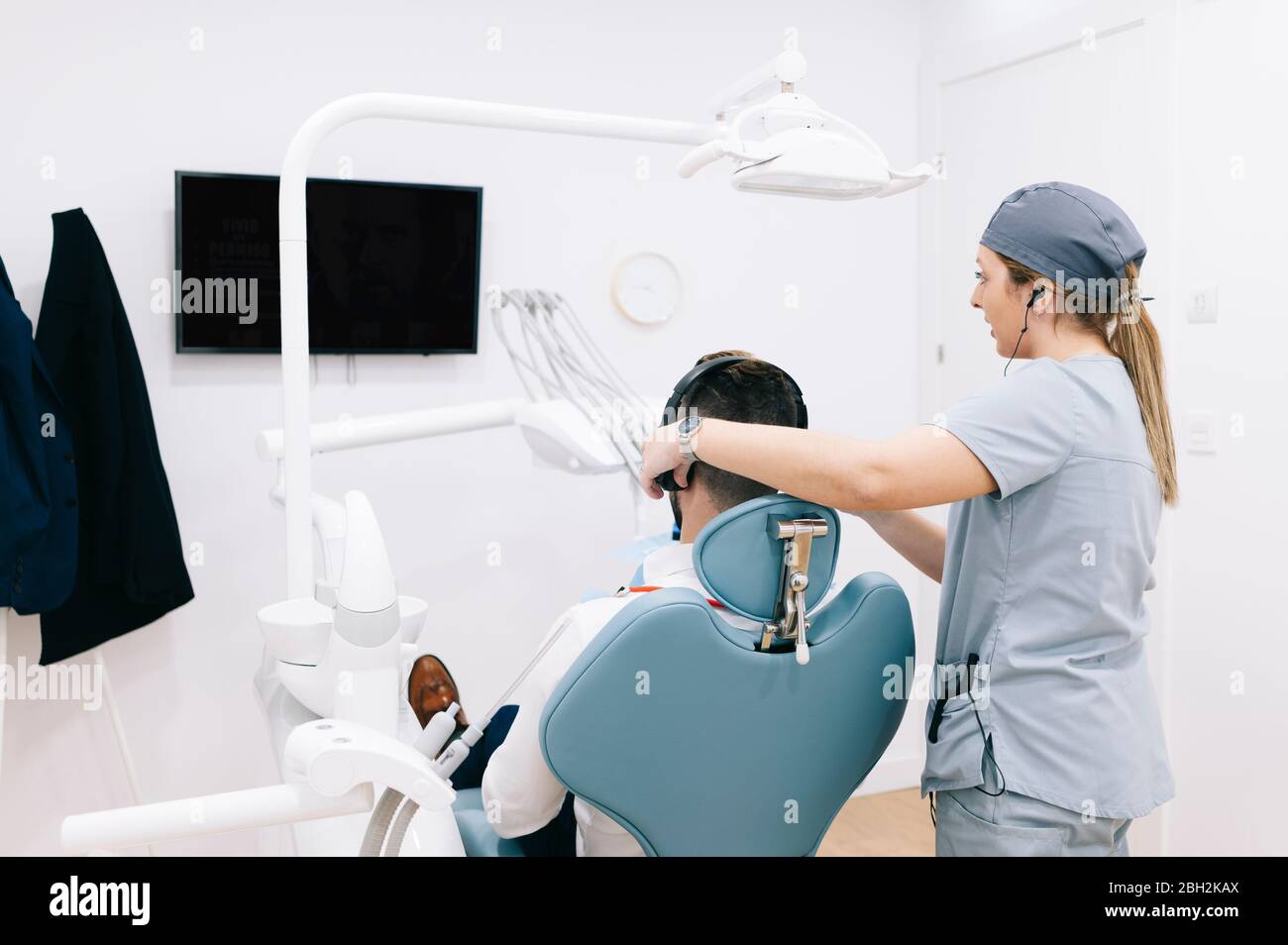 Segreteria medica preparazione del trattamento dentale indossare le cuffie sulla testa del paziente Foto Stock
