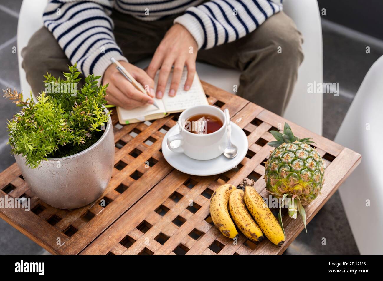 Primo piano di un uomo seduto al tavolo che prende appunti Foto Stock