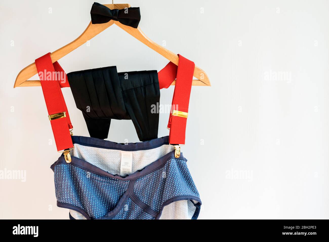 Cravatta ad arco, cummerbund, bretelle rosse con vecchi pantaloni appesi al concetto di appendiabiti; prima impressione, non giudicare, apparenze ingannevoli, superficiali. Foto Stock