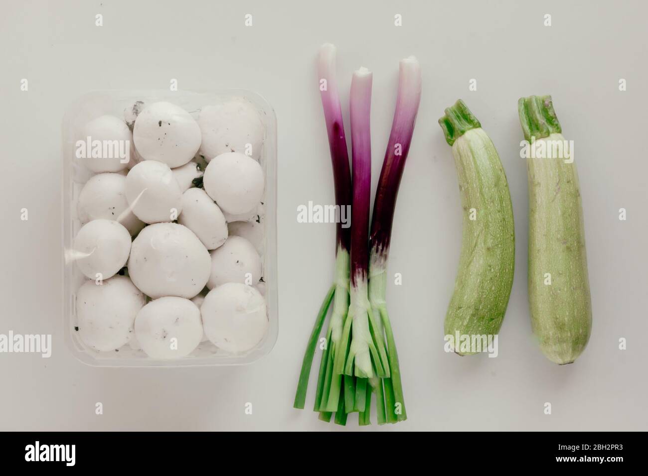 Funghi freschi anfroni bianchi in plastica e cipolle verdi scalogni o scalogno su fondo bianco. Foto Stock