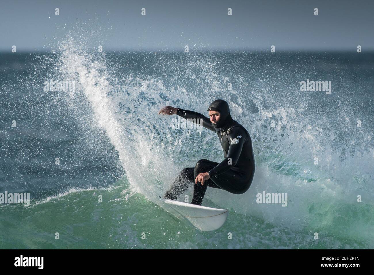 Spettacolare azione di surf mentre un surfista maturo guida un'onda al Fistral a Newquay in Cornovaglia. Foto Stock