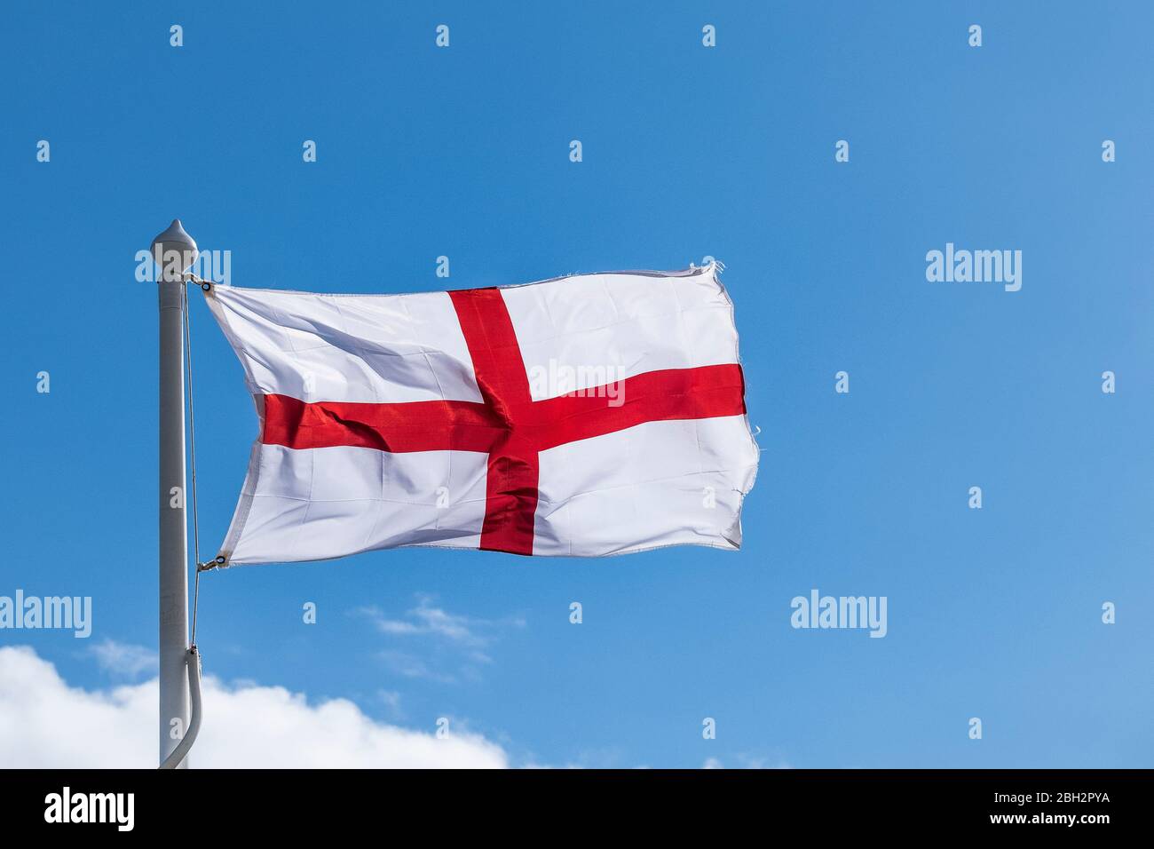 Una bandiera della Croce di San Giorgio che balbettava nel vento visto contro un cielo blu. Foto Stock