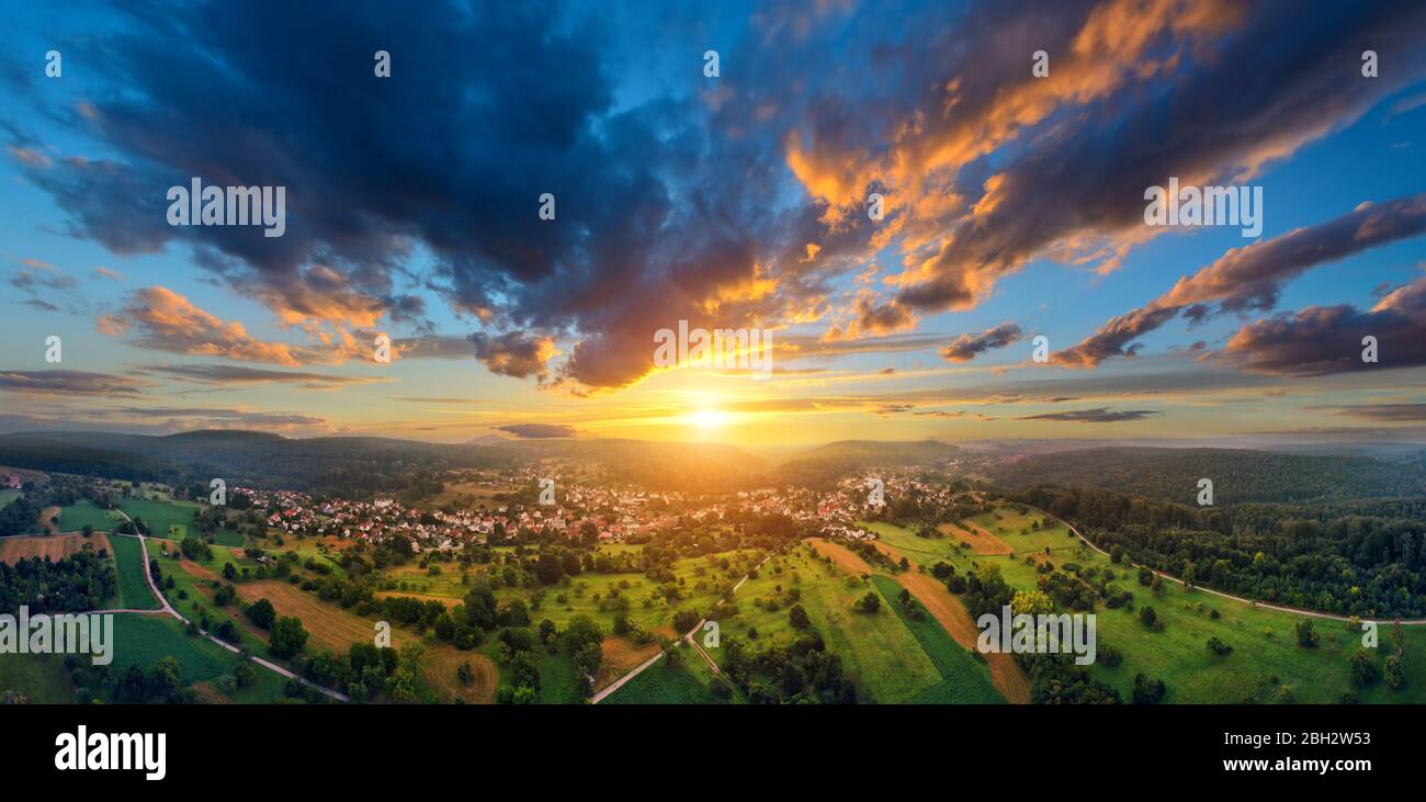 Panorama aereo di un vasto paesaggio con una piccola città ad un meraviglioso tramonto colorato con cielo drammatico Foto Stock
