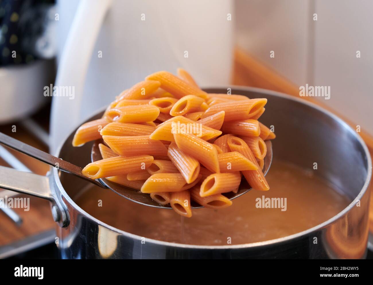 Pasta italiana senza glutine e vegan, con farina di lenticchie, mentre viene sgocciolato dal recipiente in cucina Foto Stock