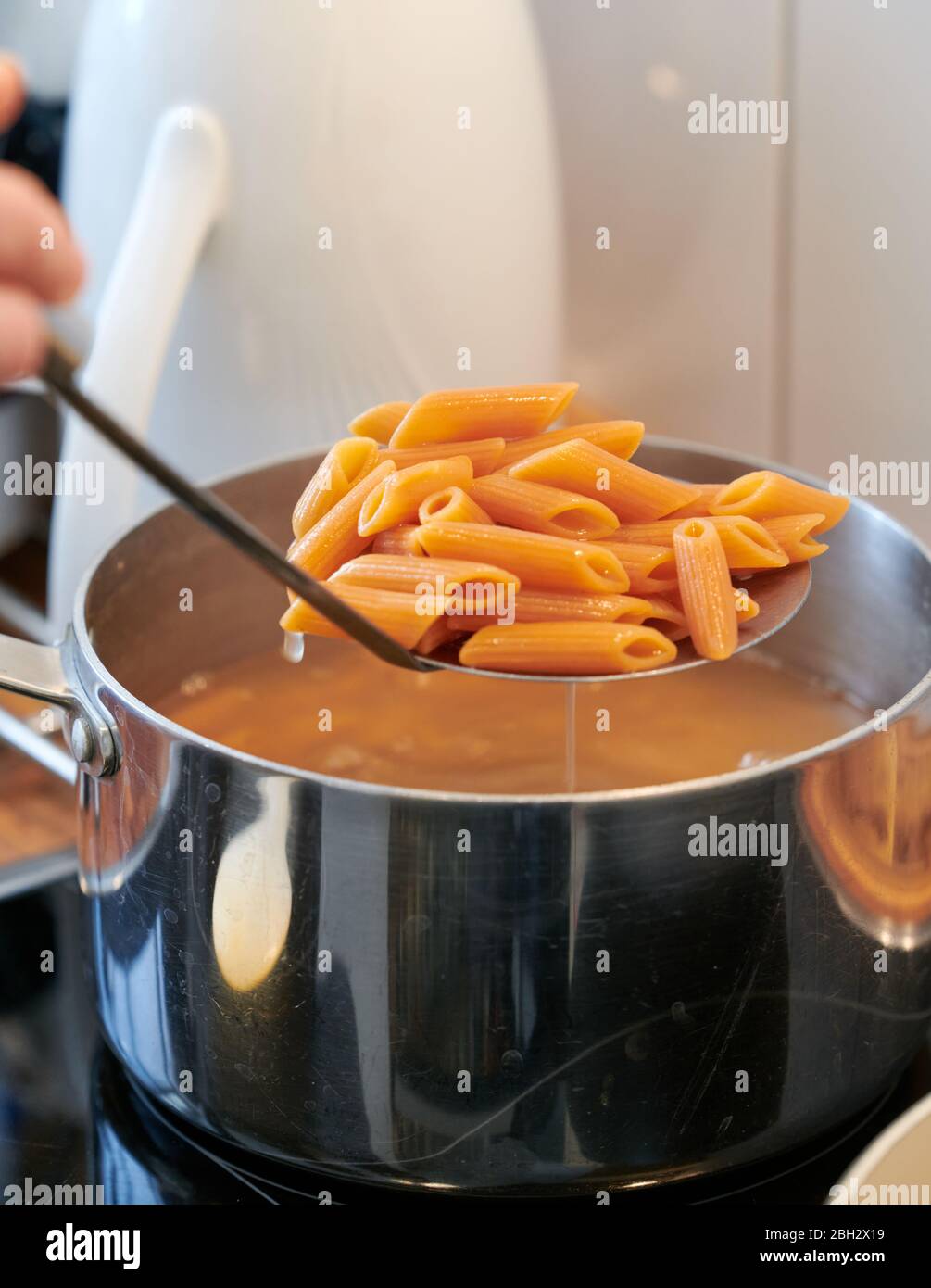 Pasta italiana senza glutine e vegan, con farina di lenticchie, mentre viene sgocciolato dal recipiente in cucina Foto Stock