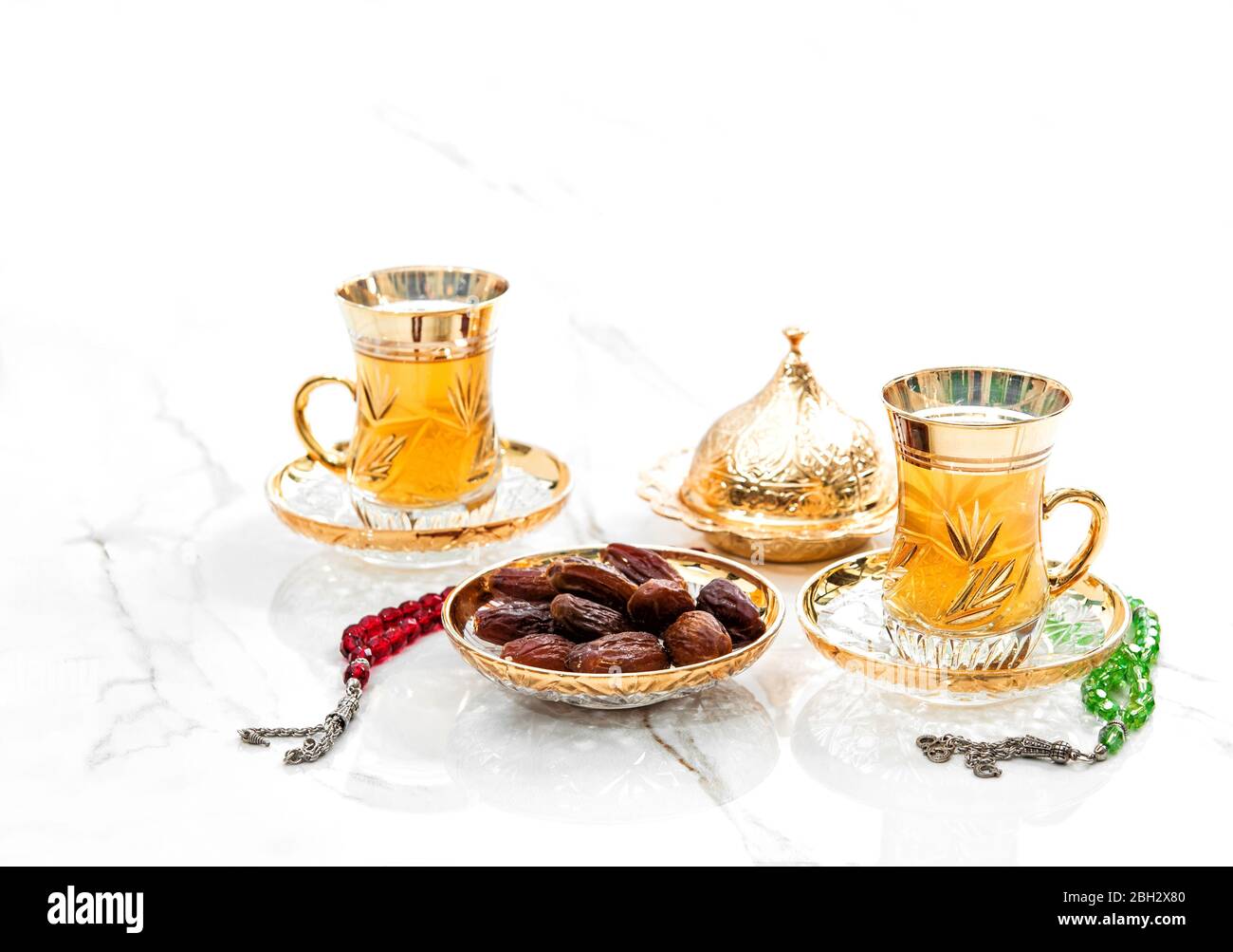 Tazze da tè dorate con datteri e decorazioni rosarie. Ramadan kareem Foto Stock